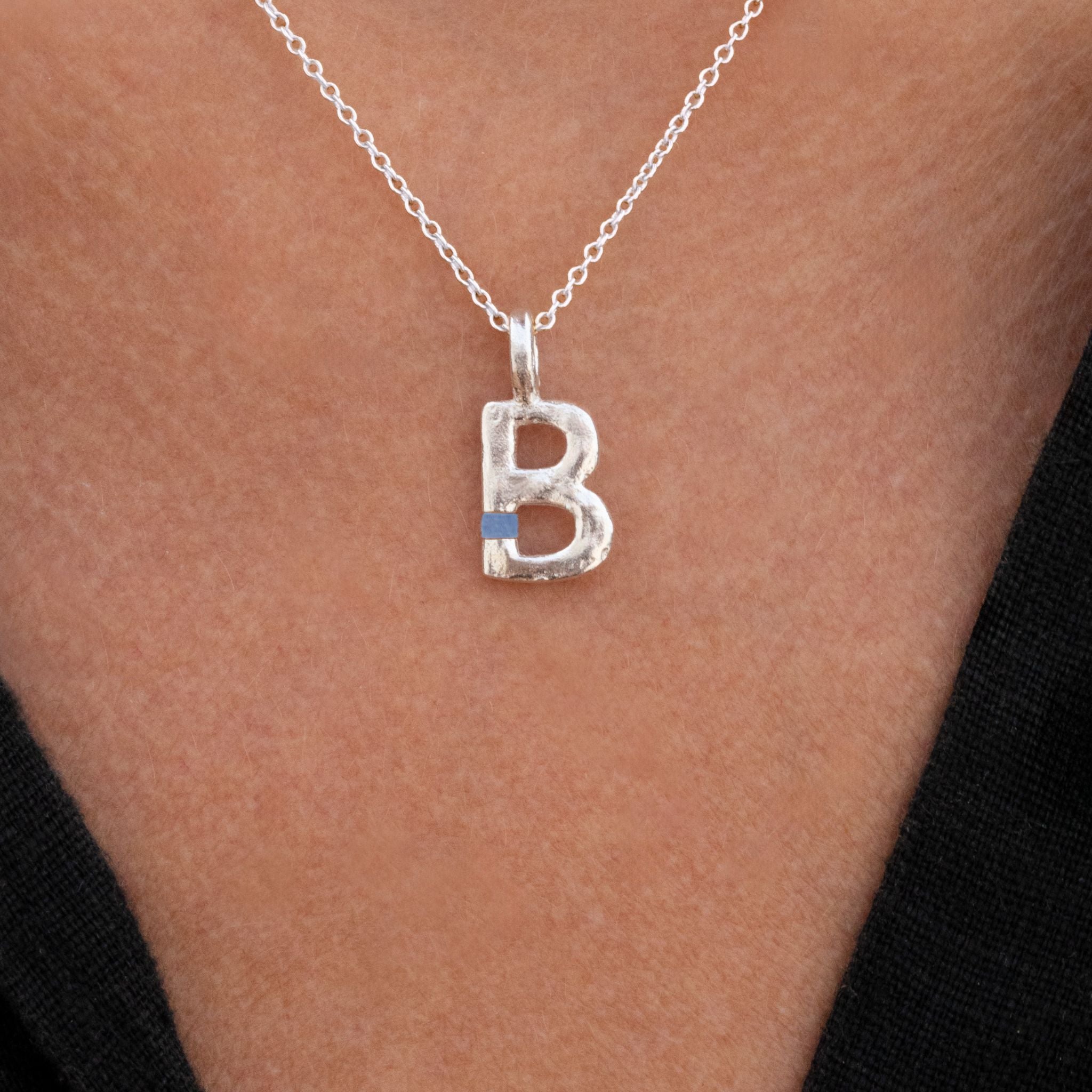 Silver necklace with a 'B' pendant on a person's neck