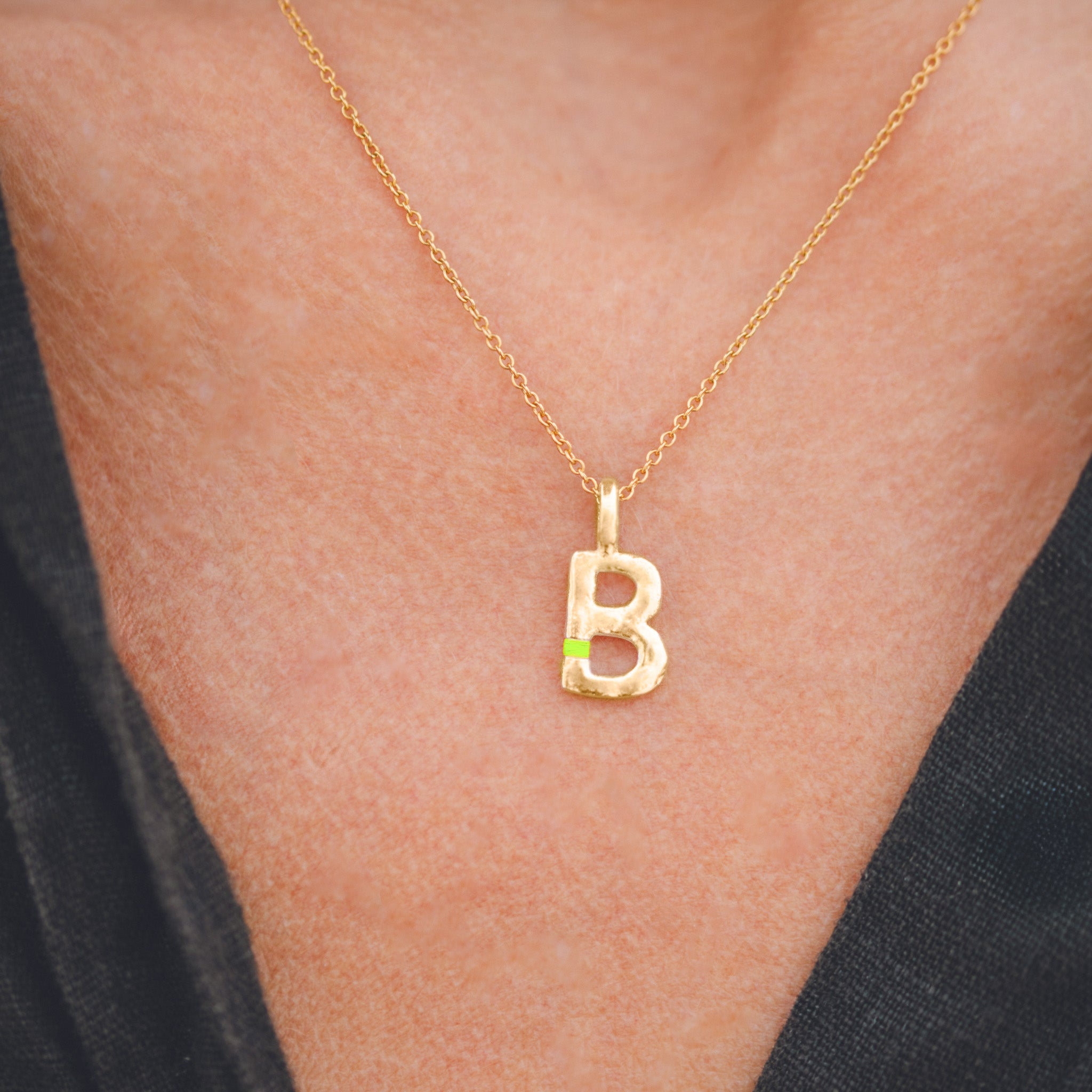 Gold necklace with a 'B' pendant on a person's neck