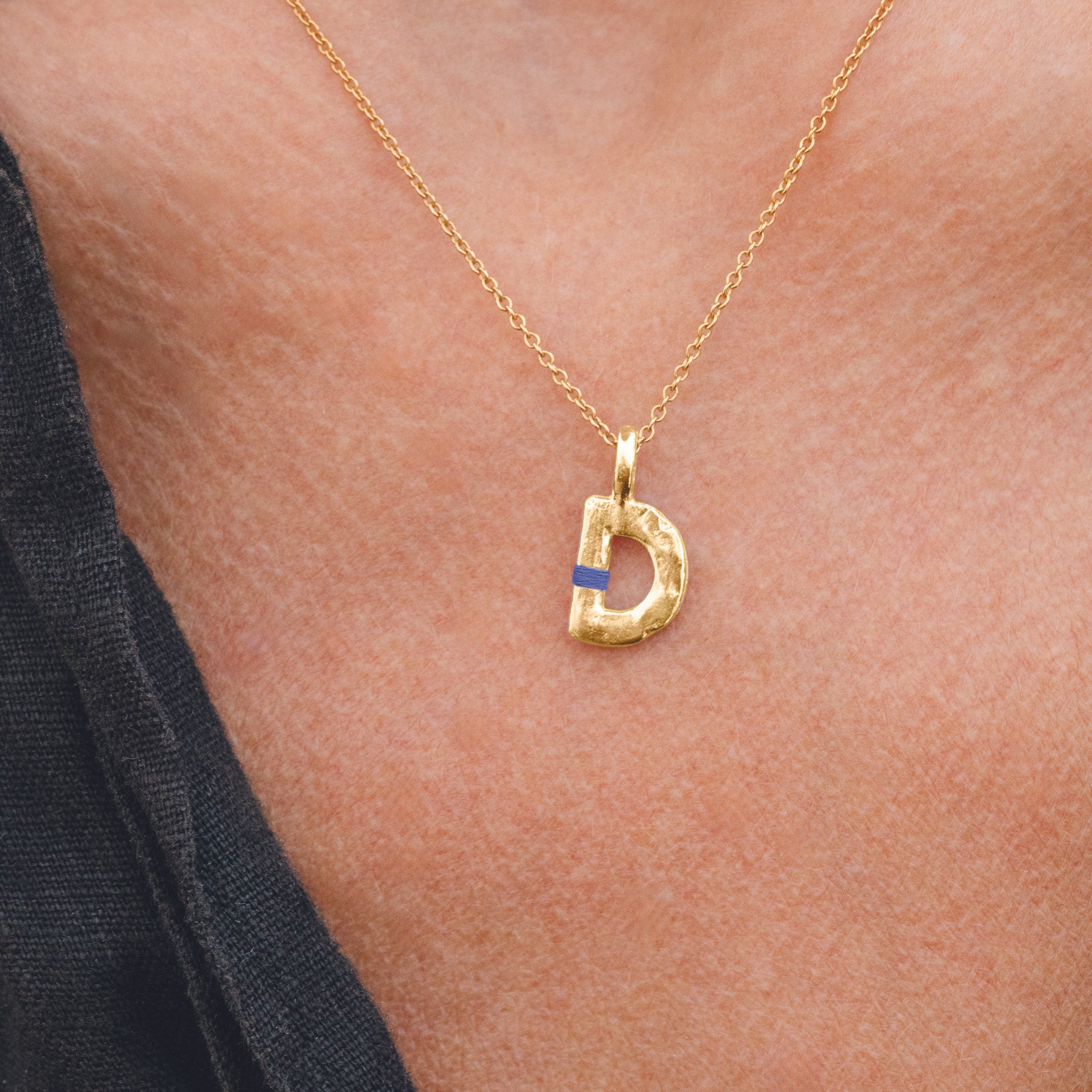 Gold necklace with a 'D' pendant on a person's neck