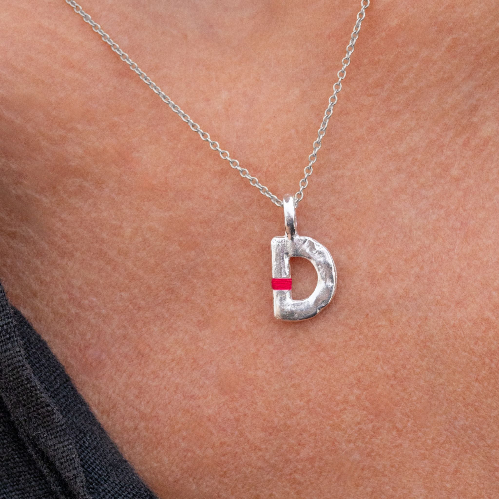 Silver necklace with a 'D' pendant on a person's neck