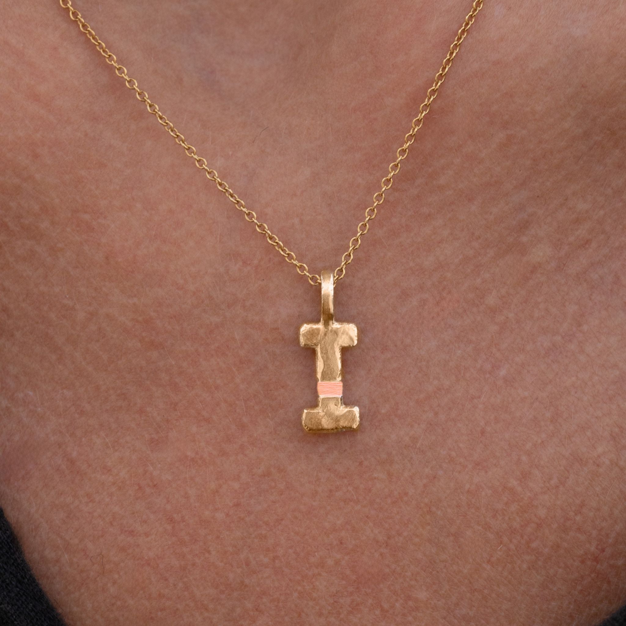 Gold necklace with a letter 'I' pendant on a person's neck.