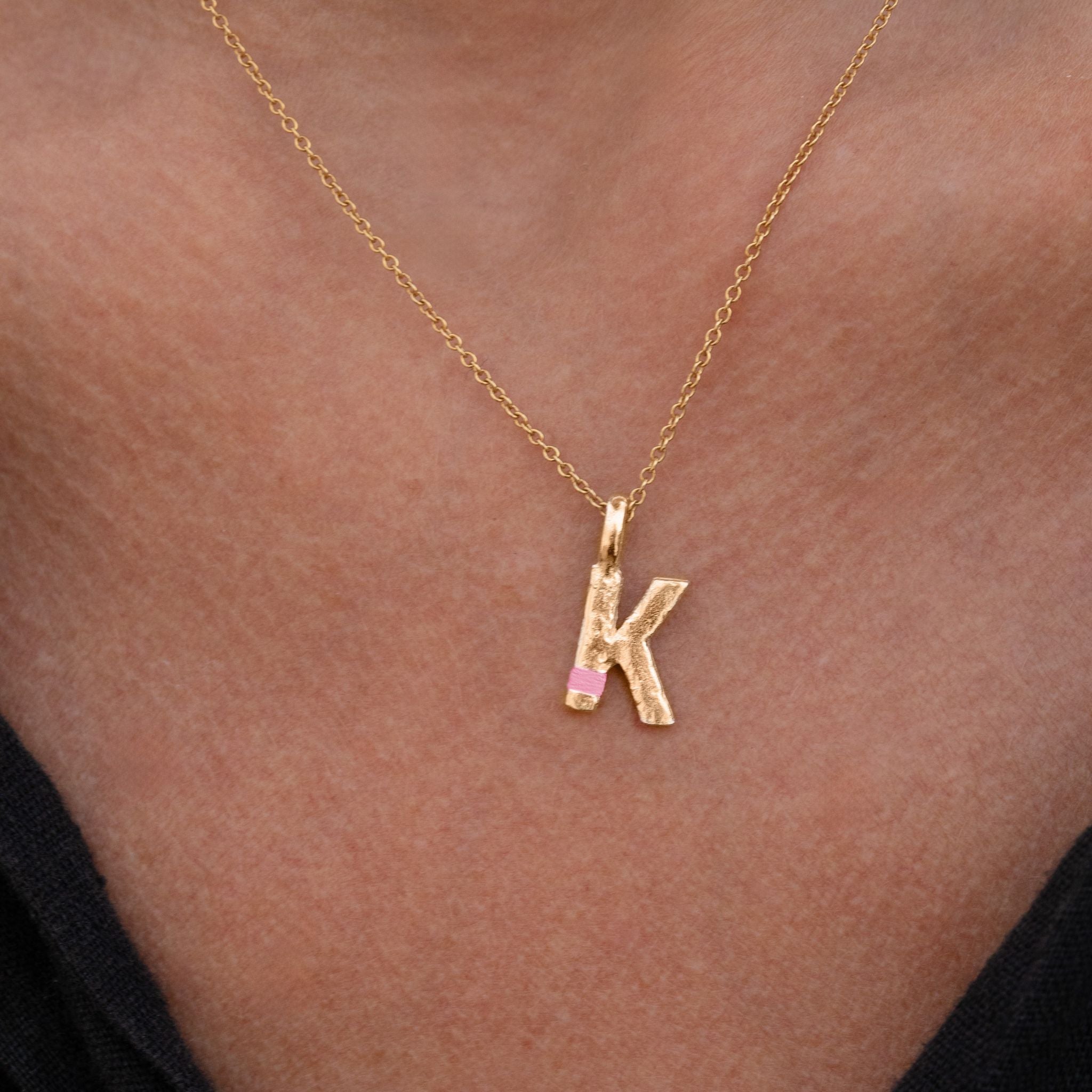 Gold necklace with a 'K' pendant on a person's neck