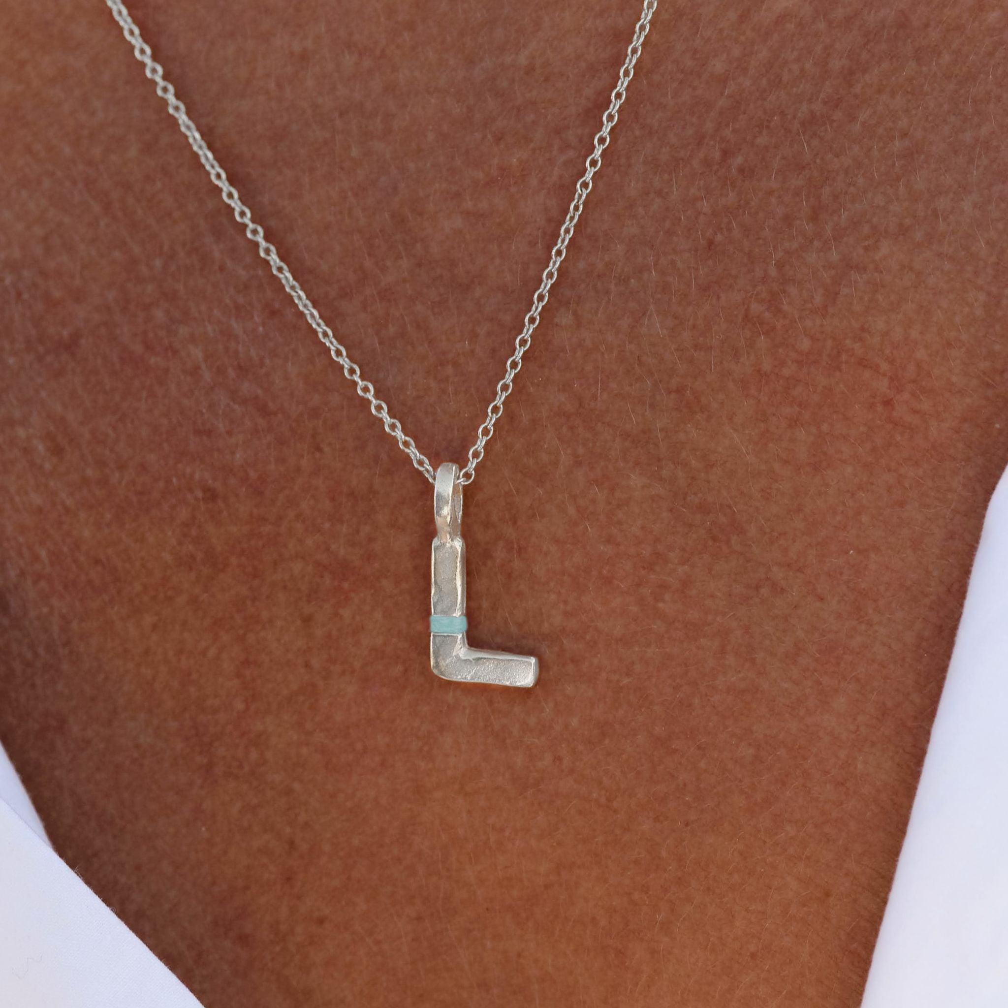 Silver necklace with a 'L' pendant on a brown background