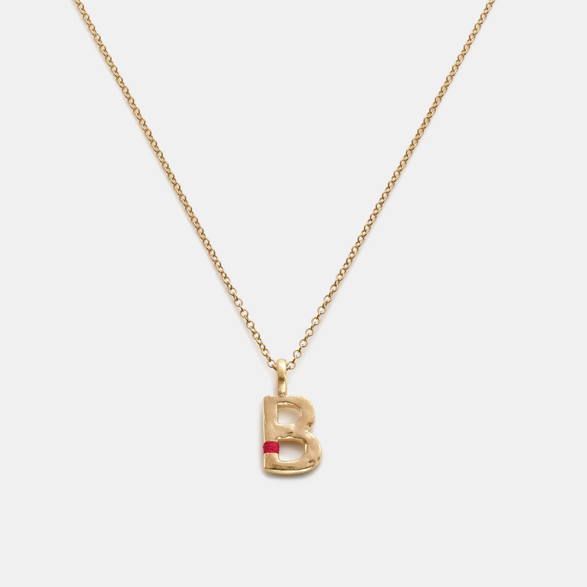 Gold necklace with a 'B' pendant on a white background