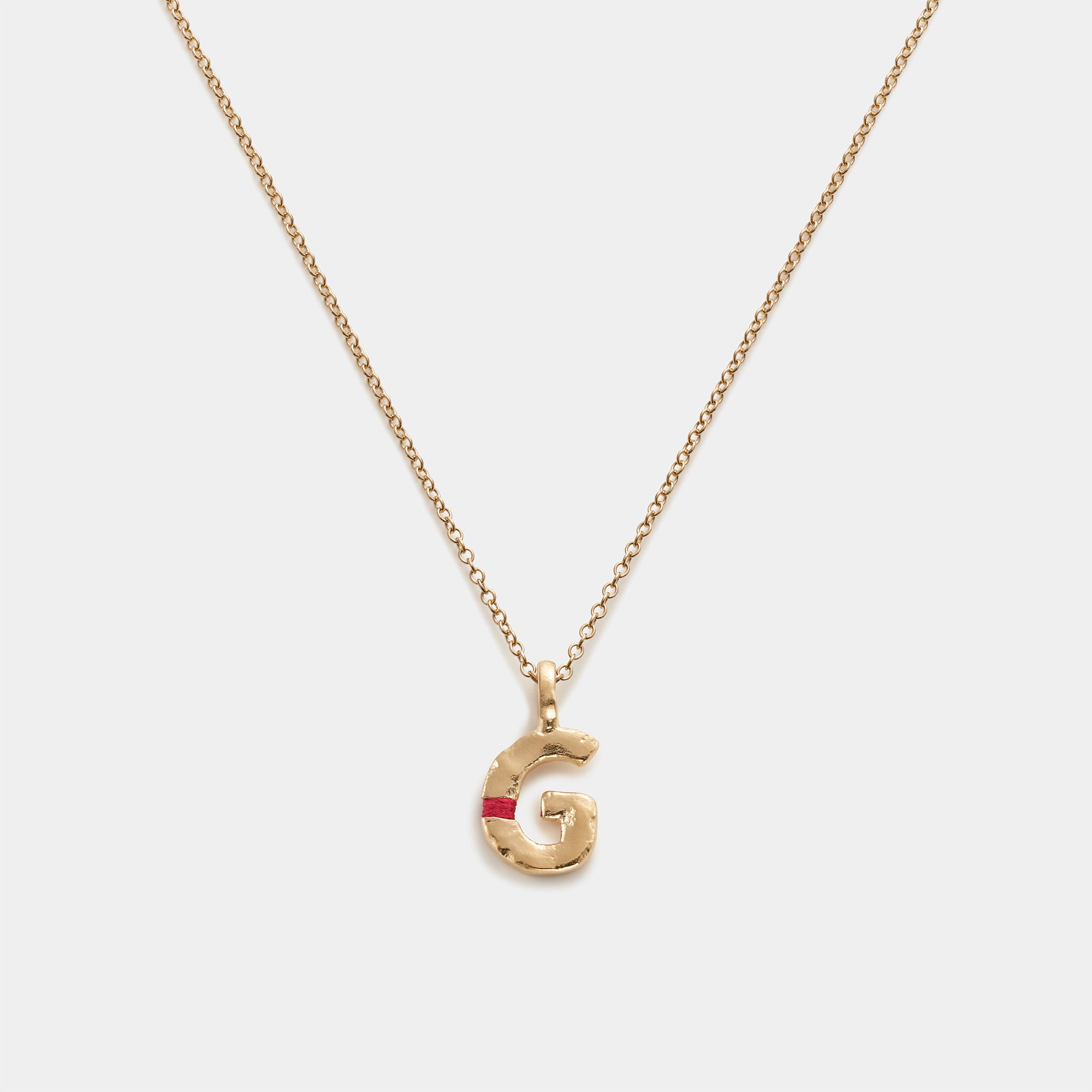 Gold necklace with a 'G' pendant on a white background