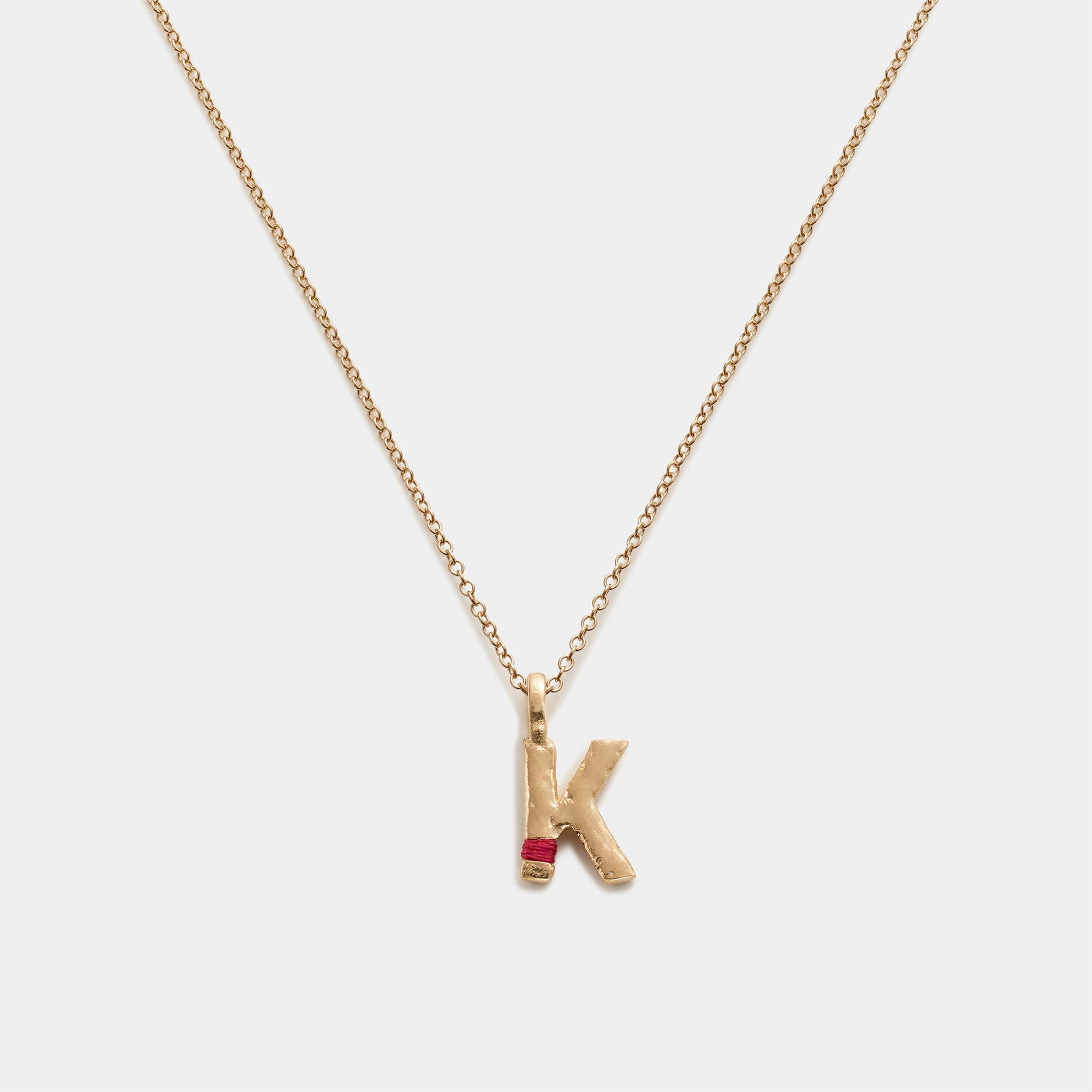 Gold necklace with a 'K' pendant on a white background