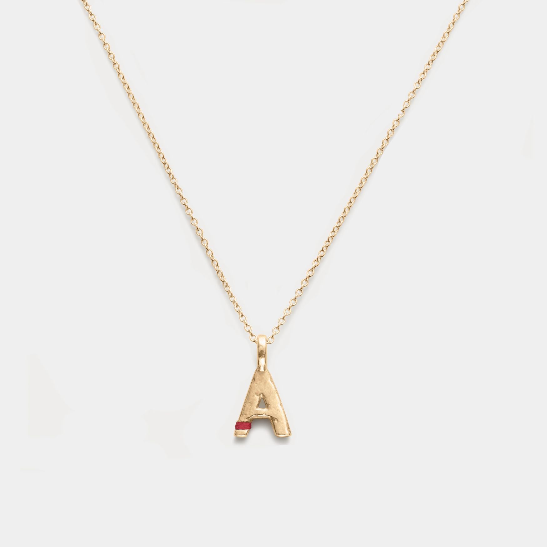 Gold necklace with a letter 'A' pendant on a light gray background