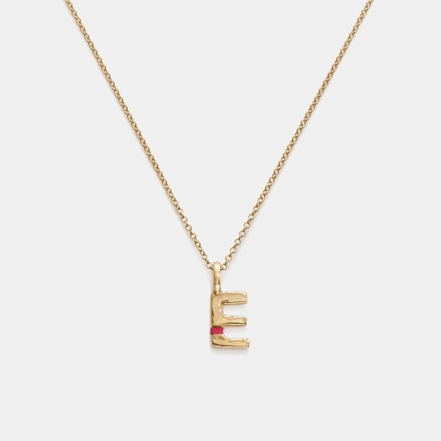 Gold necklace with 'E' pendant on a white background